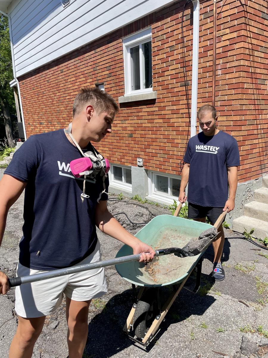 The Wastely owners loading debris into a wheelbarrow